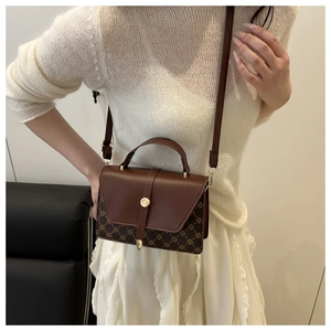 Detail of vintage crossbody bag with patchwork brown leather and gold hardware buckle