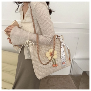 Détail du sac cabas en paille avec fleur jaune décorative et foulard en soie imprimé