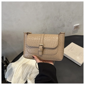Détail de la texture serpent kaki et de la boucle dorée sur un sac à bandoulière
