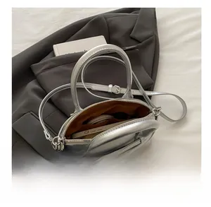 Interior view of silver textured shell bag showing storage space for phone and makeup