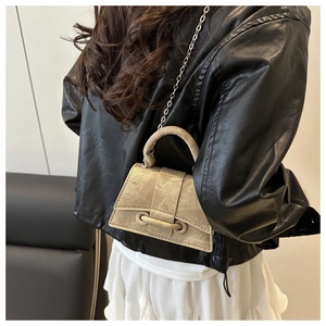 Close-up of khaki mini handbag with decorative strap and silver metal chain strap