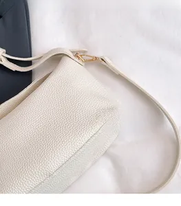 Detail of white litchi pattern leather bag with elegant gold metal hook and strap