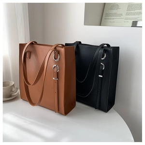 Detail of high-quality PU leather tote bags in brown and black with silver metal ring buckles