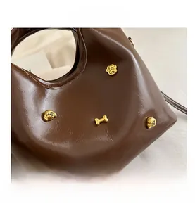 Detail of dark brown leather handbag with gold dog-shaped studs and metal accents