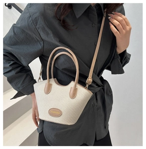 Detail of woven bucket bag with leather handles and Fashion label in summer resort style