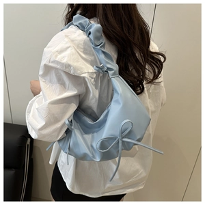 Detail of light blue cloud bag with scrunched shoulder strap and side bow design