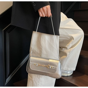 Detail of silver metallic shoulder bag with gold horsebit buckle and textured finish