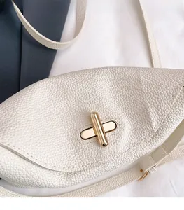 Close-up of bright gold twist-lock on creamy white lychee grain leather handbag detail