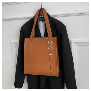 Detail of a brown tote bag with matte synthetic leather and silver metal ring hardware