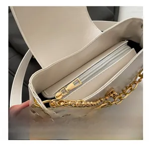Detail of white leather shoulder bag featuring gold chain and smooth interior zipper