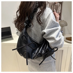 Detail of black pleated cloud bag with bow accents and matching ruffled shoulder strap