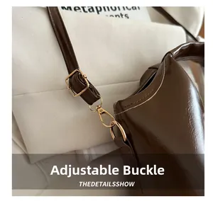 Detail of adjustable golden metal buckle and detachable strap on dark brown leather bag