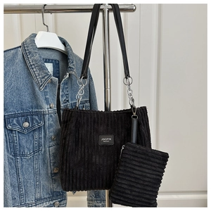 Macro detail of black corduroy tote bag set with chain strap and leather logo patch