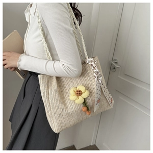Détail d'un sac cabas en paille avec fleurs décoratives et foulard en soie imprimé