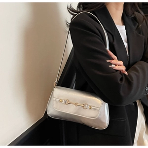 Detail of silver metallic baguette bag with vintage gold horsebit buckle decoration