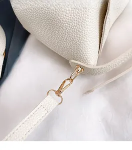 Close-up of beige lychee pattern leather handbag with premium gold spring buckle hardware