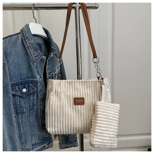 Corduroy tote bag detail with metal chain strap and blue denim jacket backdrop