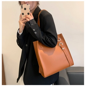 Detail of the side metal ring buckle and caramel matte leather on large tote bag
