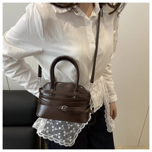 Detail of coffee brown shell handbag with silver buckles and crossbody strap