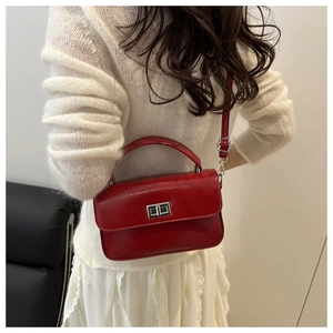 Detail of red glossy square bag featuring a silver twist lock and slim shoulder strap
