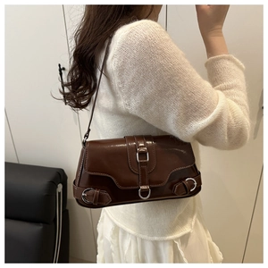 Détail d'un sac bandoulière en cuir brillant marron foncé avec boucles argentées rétro