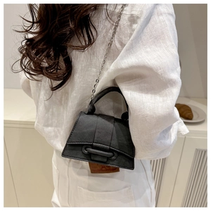 Detail of black textured hourglass bag with silver chain strap shown on model back