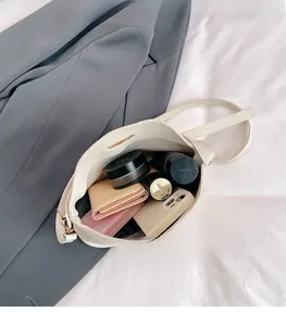 Detail showing the large interior capacity and leather texture of the off-white pillow bag