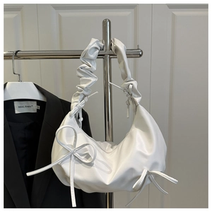 Close-up of white ruffled handle and bow ribbon detail on elegant crescent cloud shoulder bag