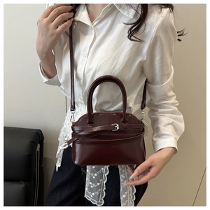 Close-up of deep wine red shell handbag in glossy patent leather with top handle