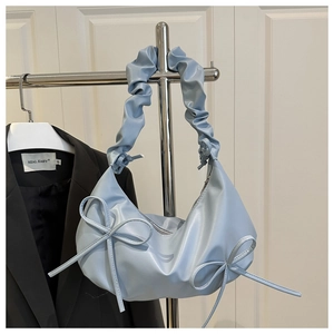 Close-up of light blue cloud bag featuring pleated straps and twin decorative bows