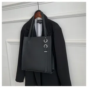Detailed view of black faux leather tote bag with silver rings and stylish strap detail