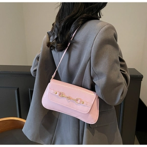 Pink underarm bag with gold horsebit hardware worn by model in a grey suit