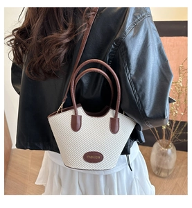 Detail of woven bucket bag with leather handles shown on model in indoor setting