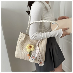 Détail du sac seau tissé avec pendentif tournesol et accessoire de foulard en soie imprimé