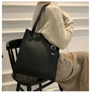 Detail of black leather tote bag with unique asymmetric cutout and silver metal ring