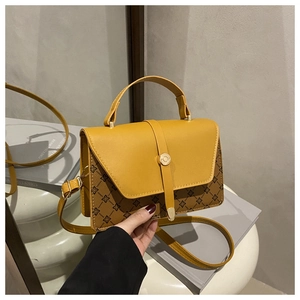 Detail of contrast color handbag featuring mustard yellow flap and brown floral pattern