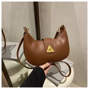 Dettaglio di una borsa a tracolla in pelle marrone con fibbia in metallo dorato a triangolo