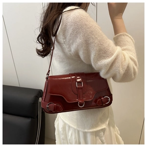 Détail du sac baguette en cuir verni bordeaux avec boucle rétro porté à l'épaule