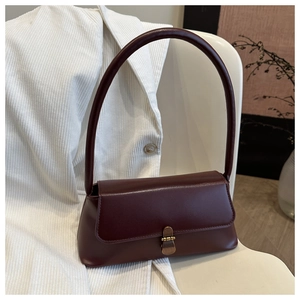 Close-up of deep wine red matte leather texture and vintage brass buckle on a shoulder bag