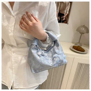 Détail du sac en dentelle bleu clair avec papillons 3D et cordon de serrage perlé élégant