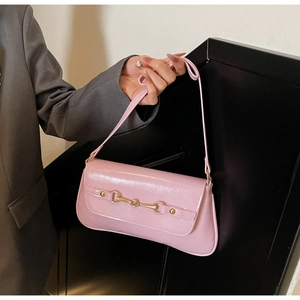 Detailed view of pink patent leather shoulder bag featuring a gold horsebit buckle detail