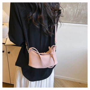 Detail of pink pebbled leather crossbody bag with metal buckle and shoulder strap