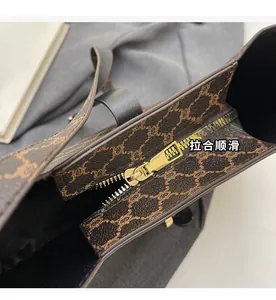 Dettaglio macro della cerniera in metallo dorato su borsa in tela con stampa vintage