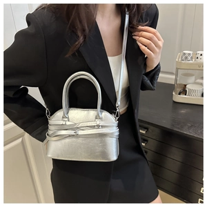 Detail view of silver shell bag showing metallic texture and decorative strap design