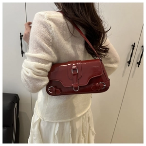 Détail du sac à bandoulière en cuir verni bordeaux avec finition brillante et boucle argentée