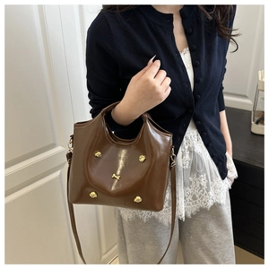 Detail of brown leather handbag with gold dog rivets and bone charm on shoulder strap