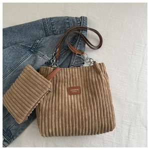 Macro detail of brown corduroy tote set featuring leather brand tag and metal chain strap