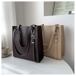 Detail of minimalist tote bags in dark brown and beige with silver metal buckles