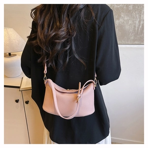 Pink lychee grain leather bucket bag shown on a model in a minimal indoor setting