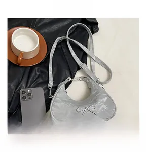 Detail view of silver crescent moon bag with metallic texture and bow decoration